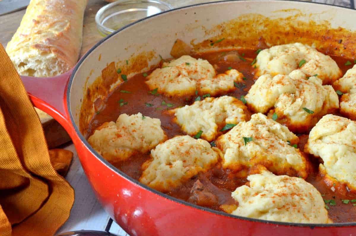 A pot of stew with dumplings on top.