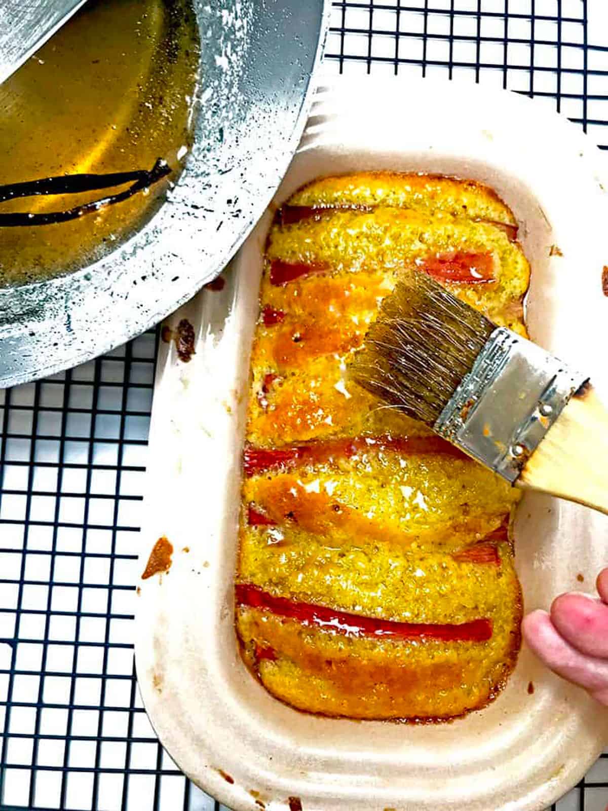 Brushing vanilla simple syrup on top of a rhubarb pound cake.