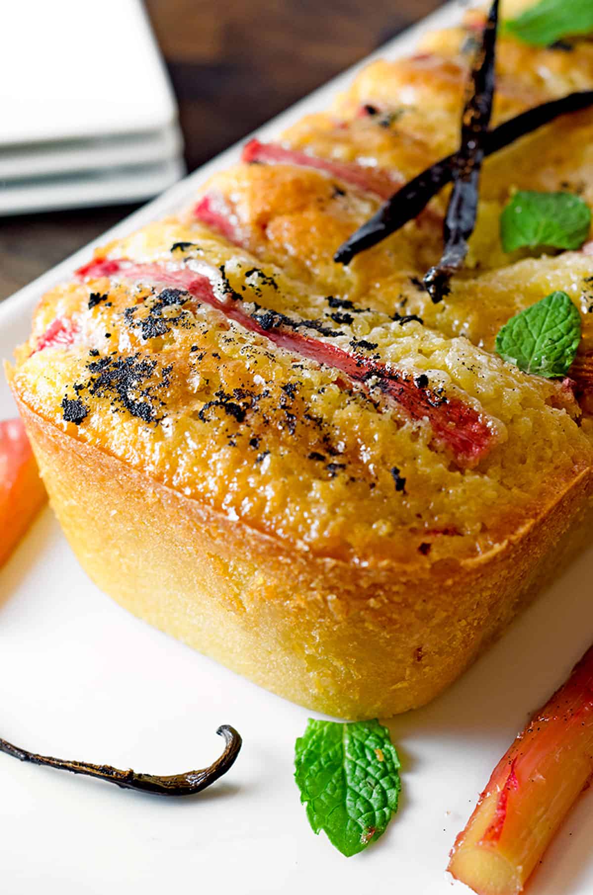 Closeup of a rhubarb pound cake with a vanilla bean garnish.