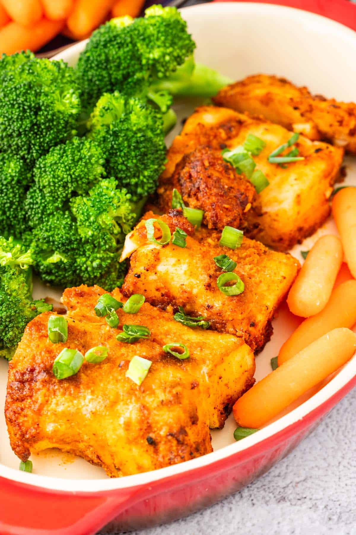 A dish of air fryer cod with broccoli and carrots.