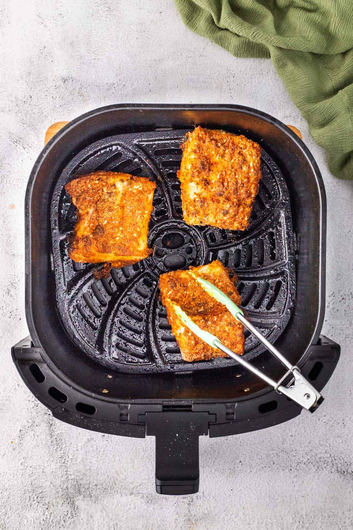 Some fish cooking in an air fryer basket.
