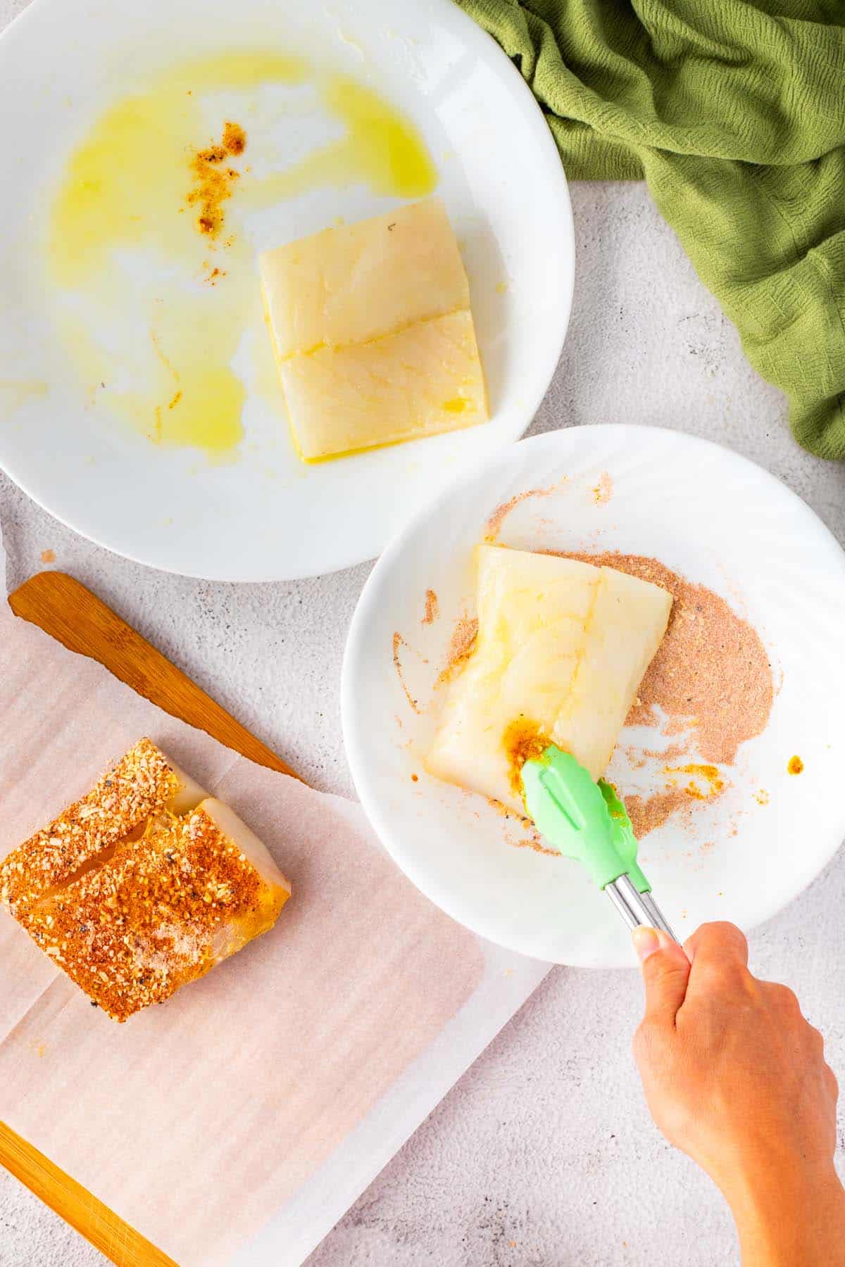 Coating cod fillets with a dry seasoning rub.