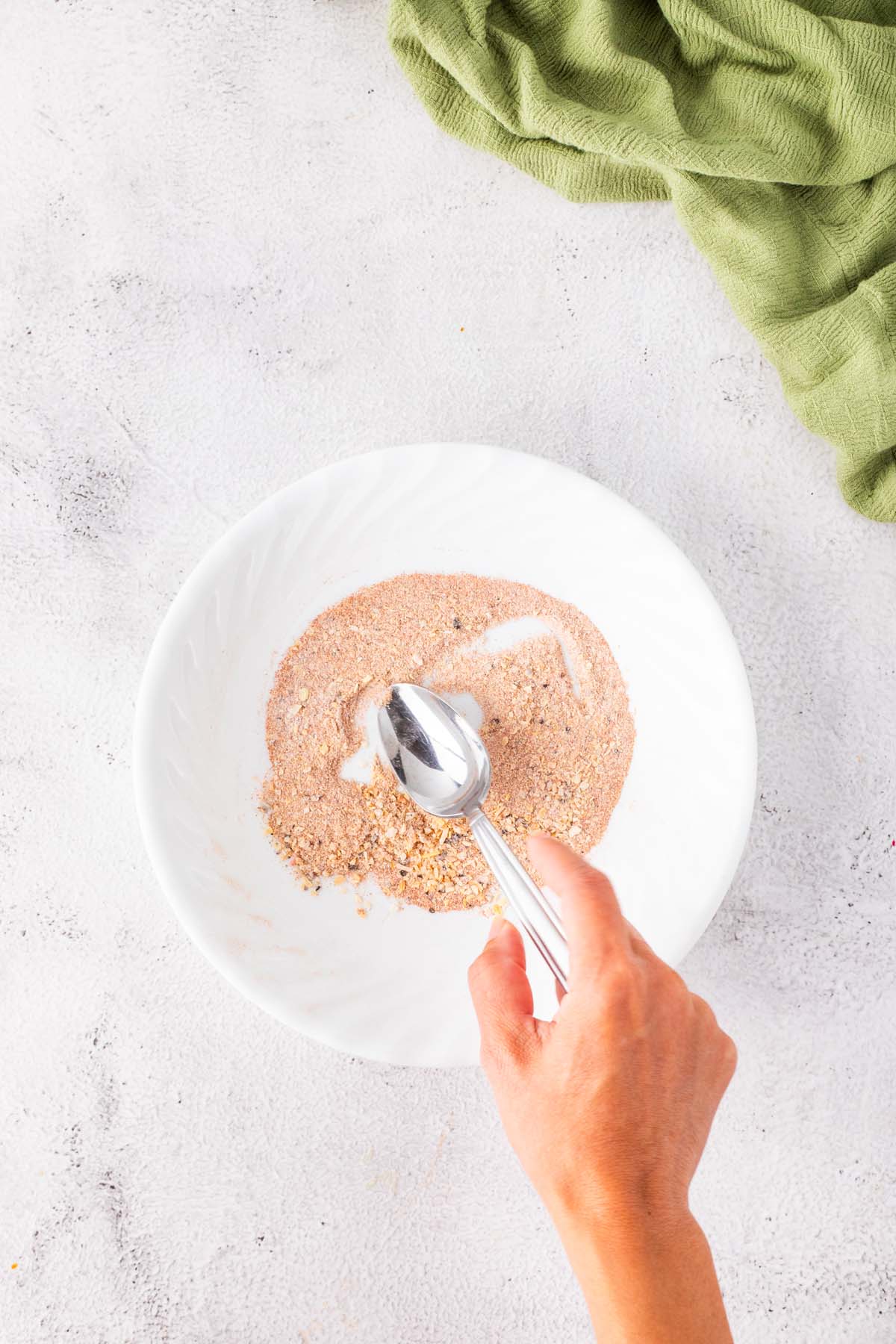A spoon, mixing some seasoning in a small bowl.