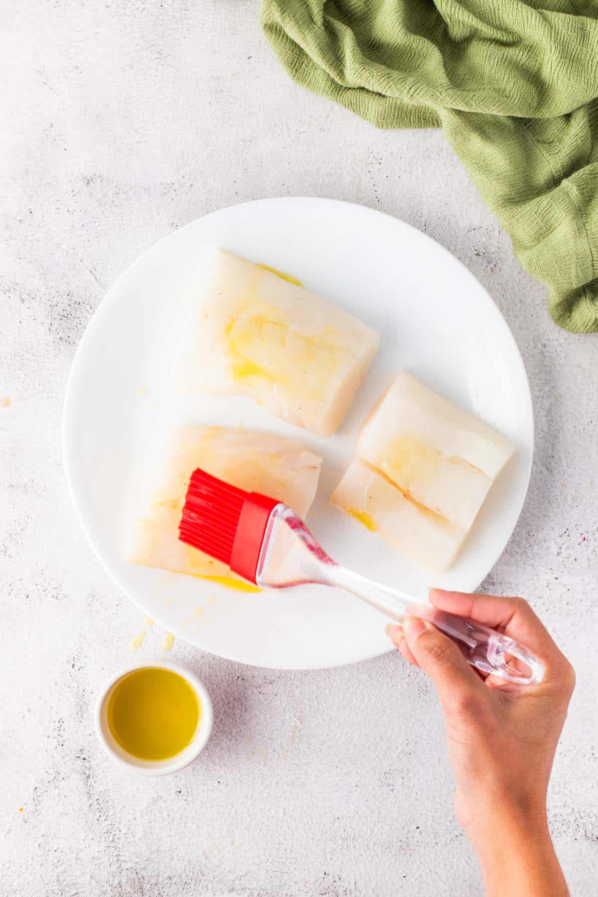 Brushing olive oil on to some fish fillets.