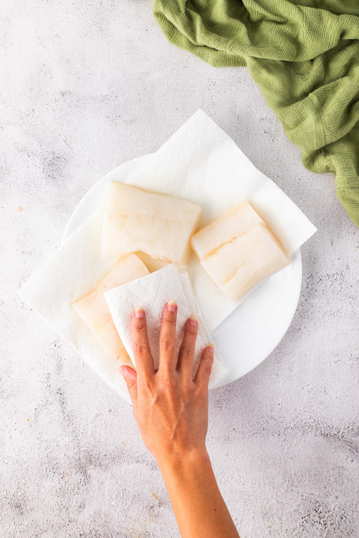 Using a paper towel to pat dry some fish fillets.