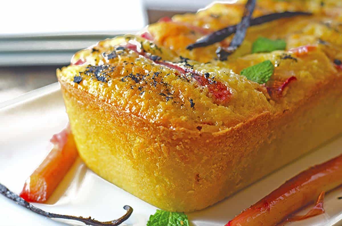 Side angle of a golden-colored pound cake with vanilla bean garnish on top.