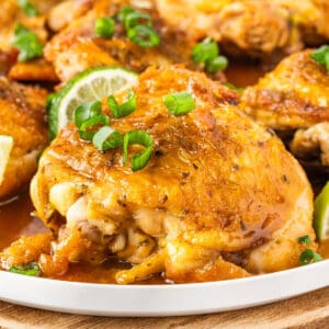 A golden-brown piece of chicken with lime and green onion garnish.