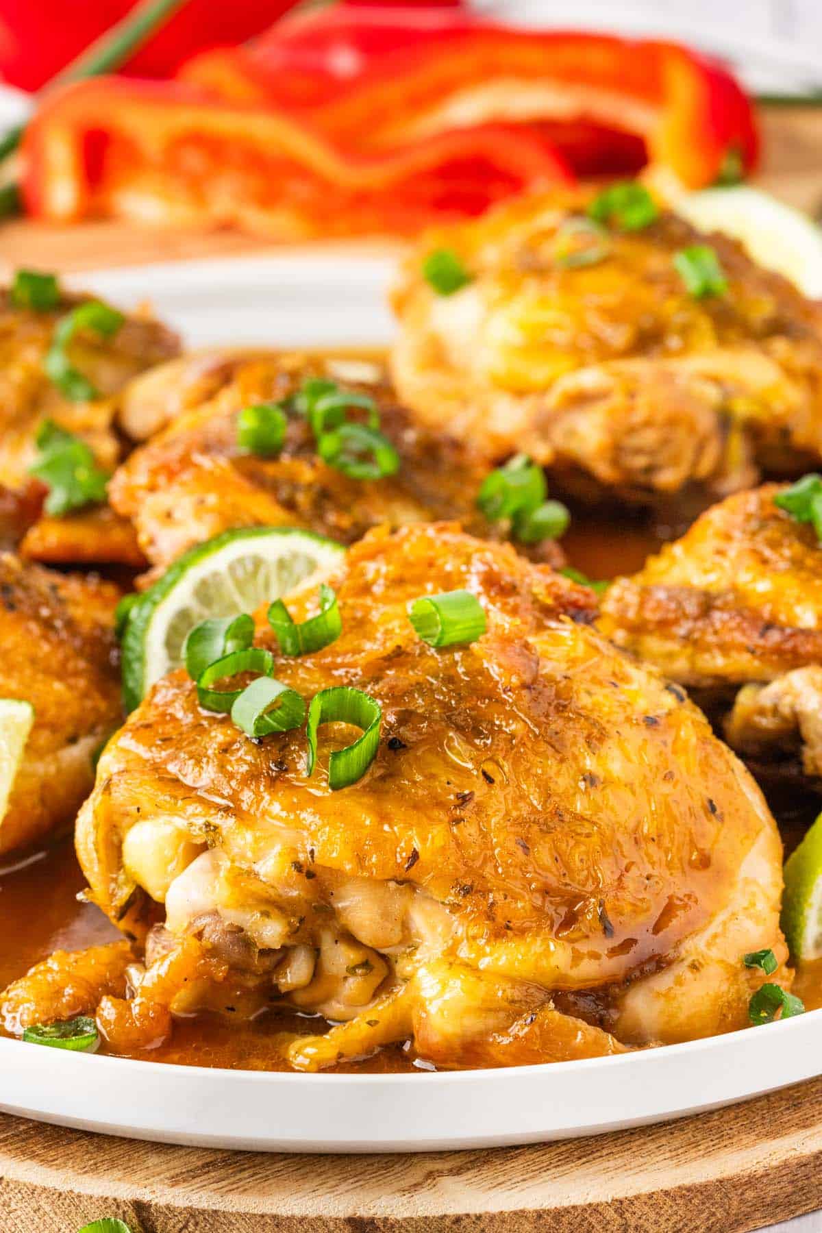 A plate of of golden-brown chicken garnished with green onion and lime slices.
