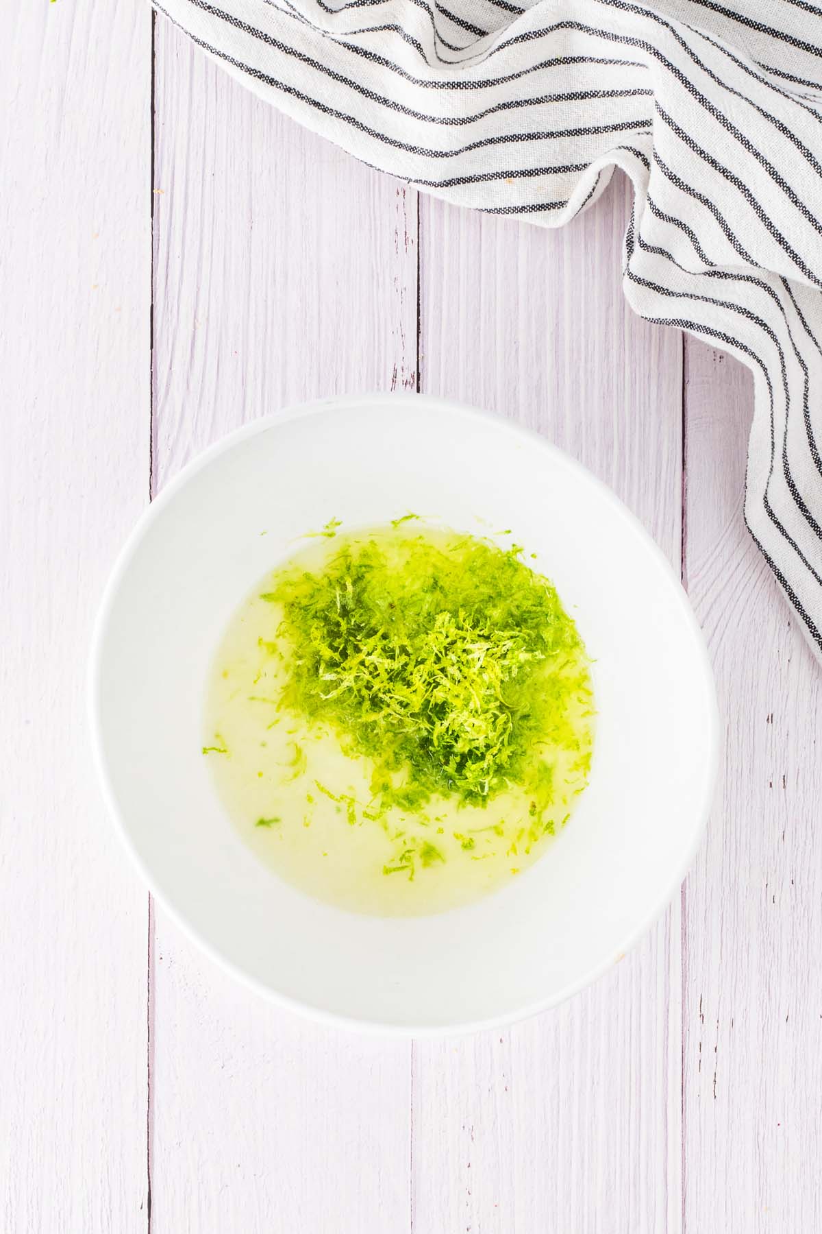 A mixing bowl with fresh lime juice and lime zest.