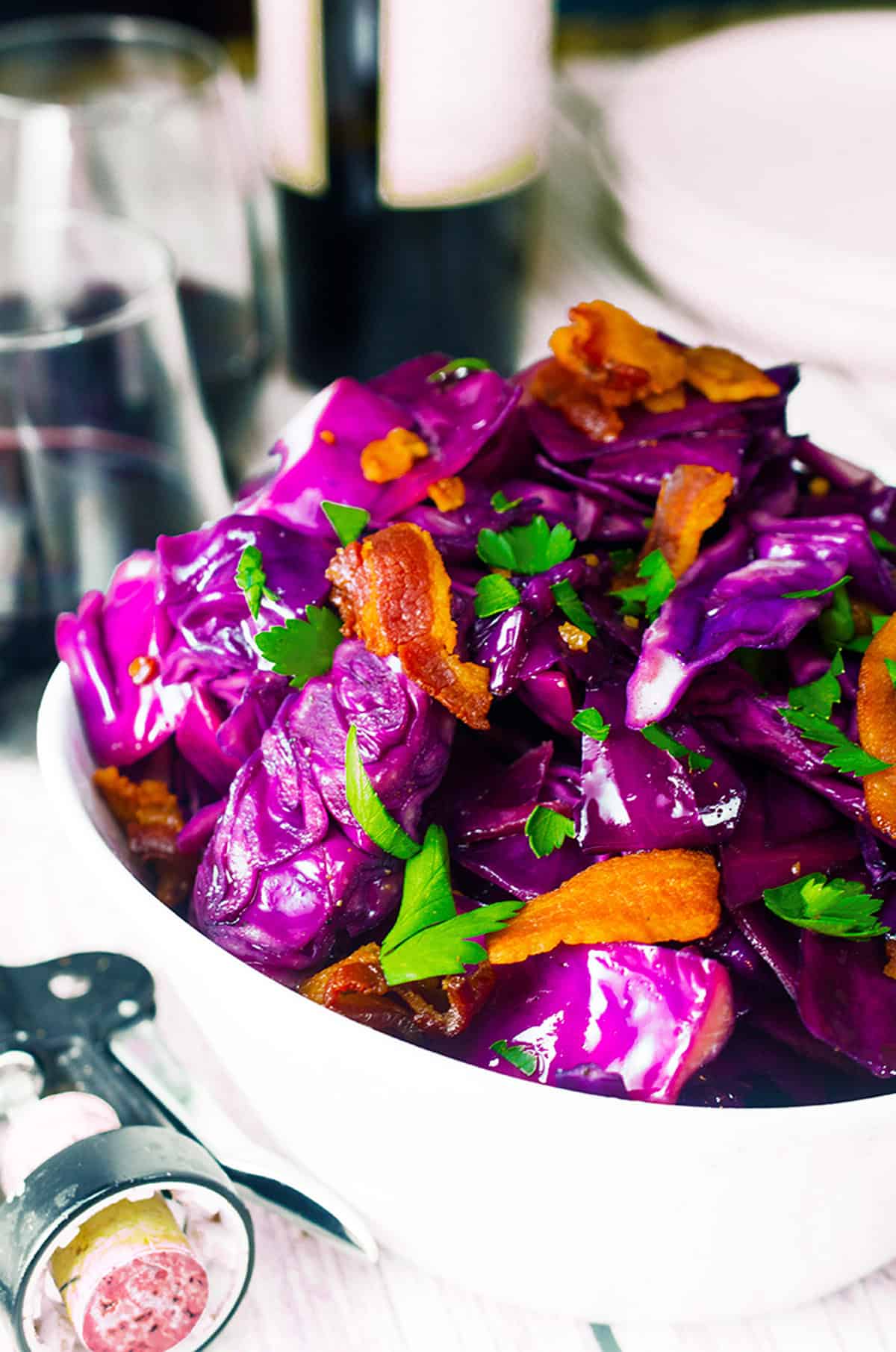 A bowl of purple fried cabbage with bits of bacon and parsley.