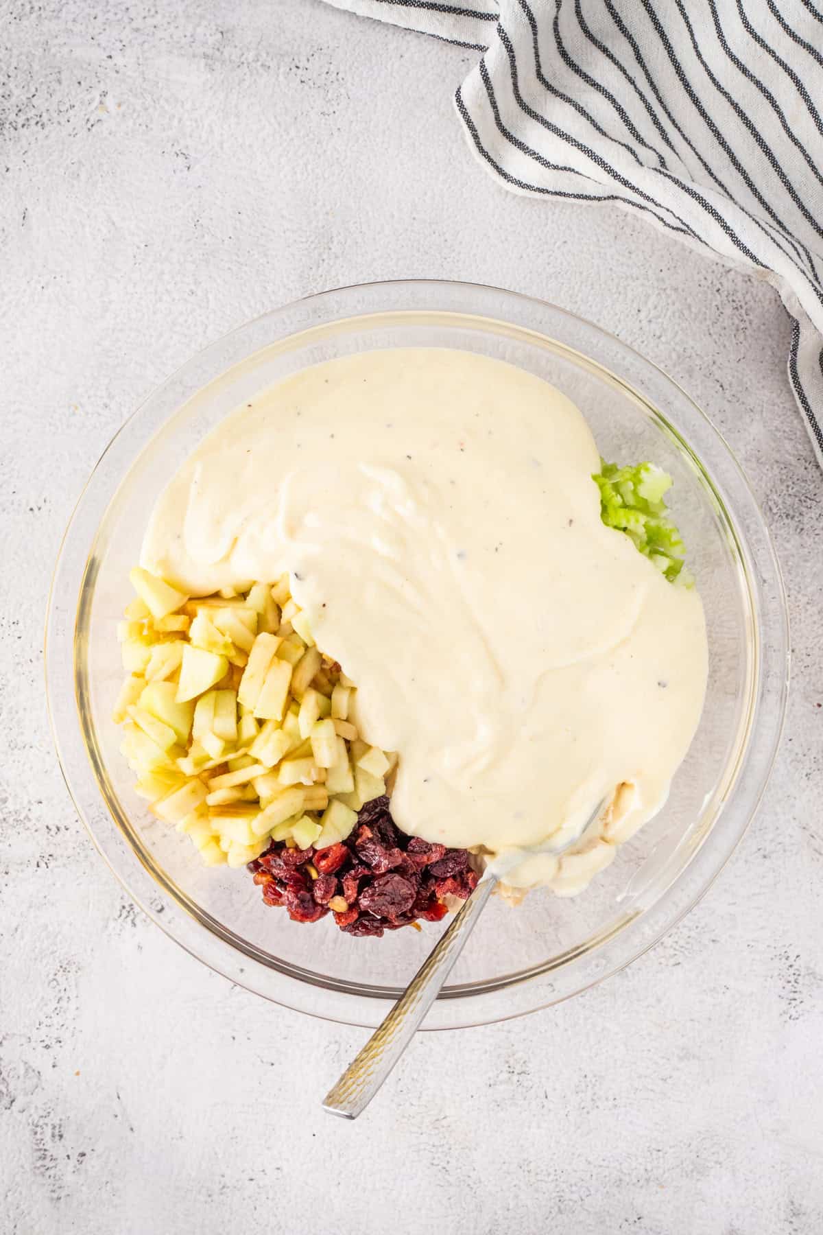 Adding mayonnaise dressing to chicken salad in a mixing bowl.