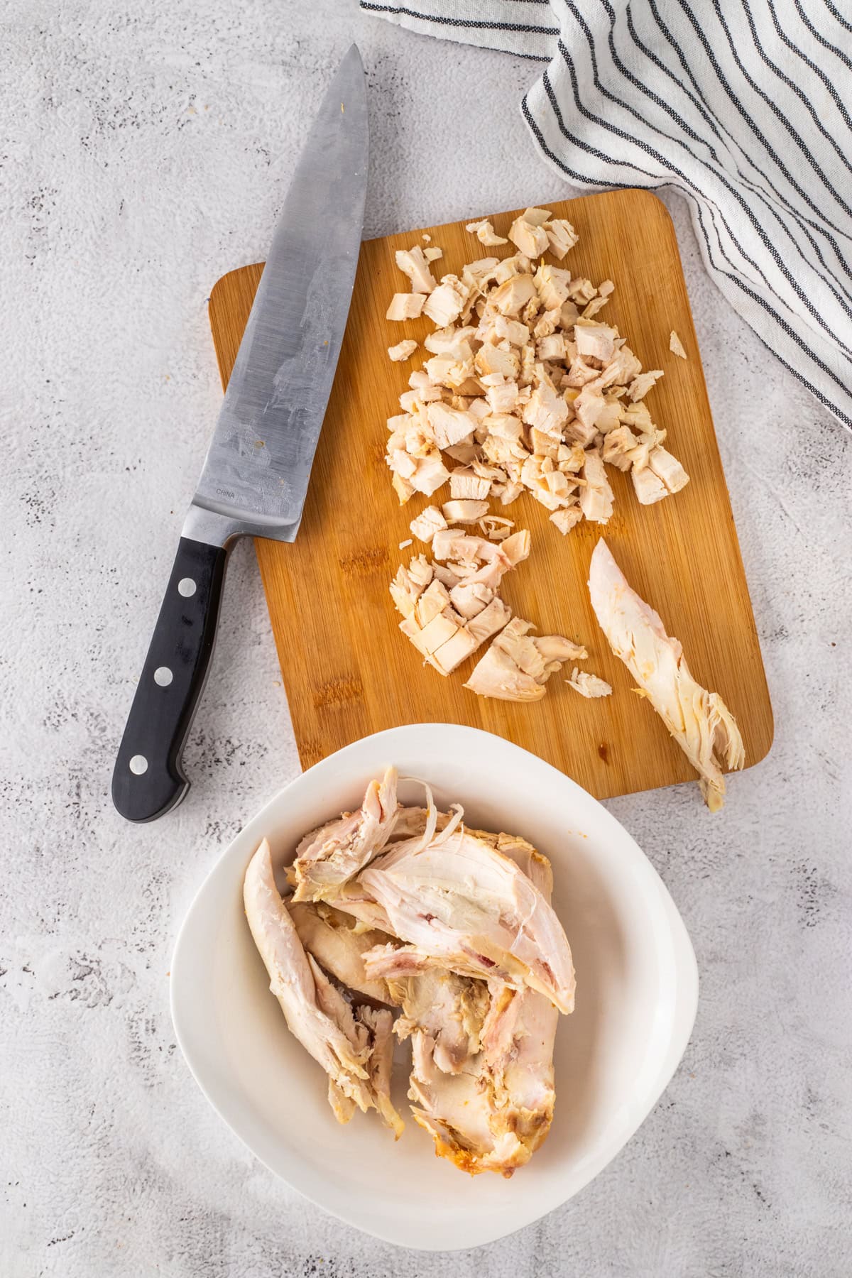 Some shredded and chopped chicken on a cutting board.