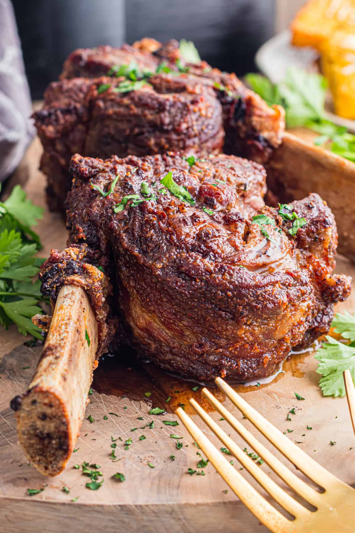 Two short ribs on a cutting board, garnished with fresh parsley.