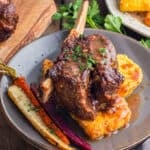 A plate of short ribs over polenta with rainbow carrots.