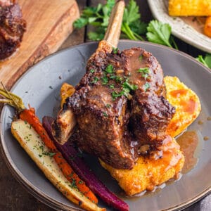 A plate of short ribs over polenta with rainbow carrots.