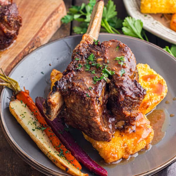 A plate of short ribs over polenta with rainbow carrots.