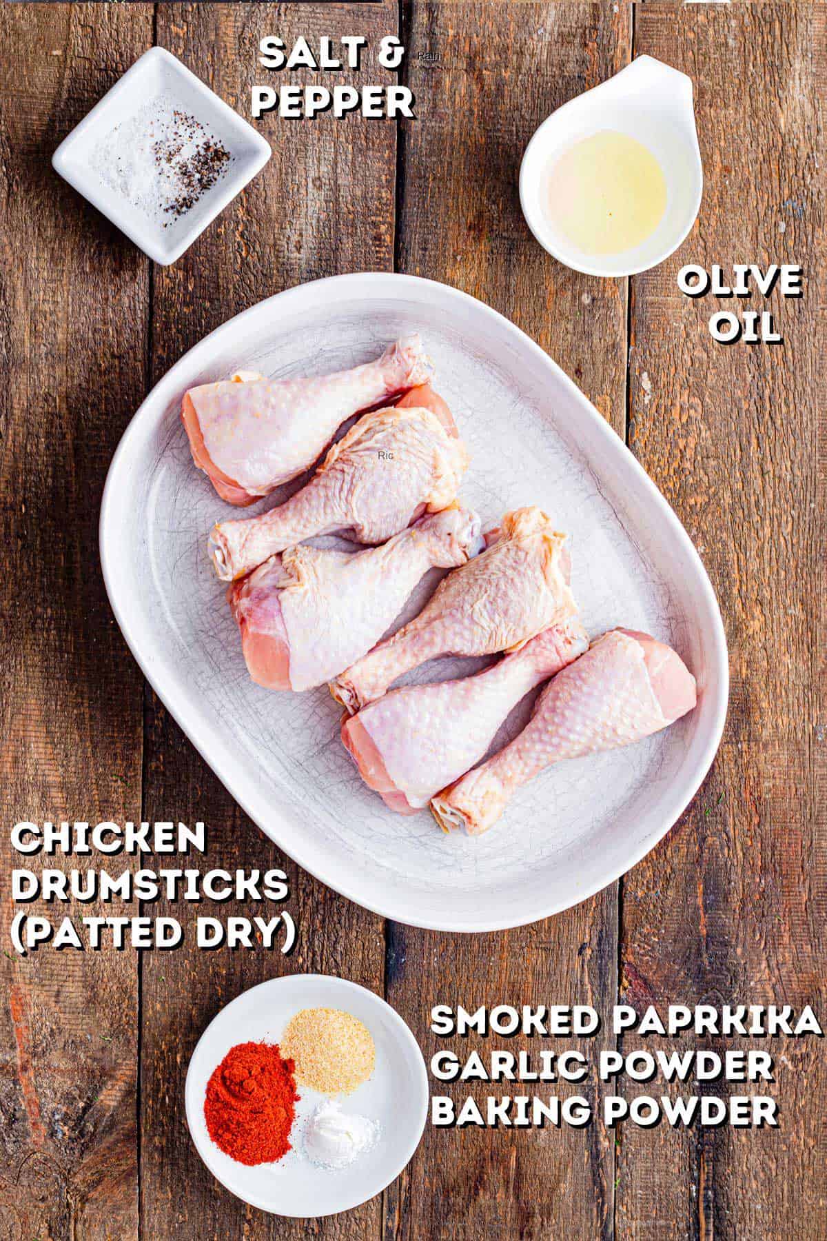 Some uncooked chicken drumsticks with seasoning and olive oil on the side.