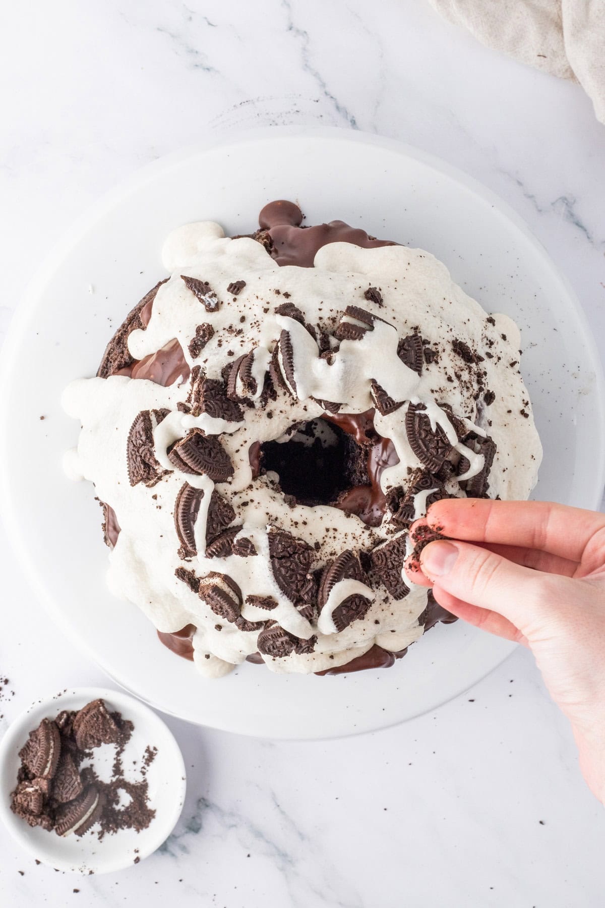 Adding Oreo pieces to the top of a cookies and cream Bundt cake.
