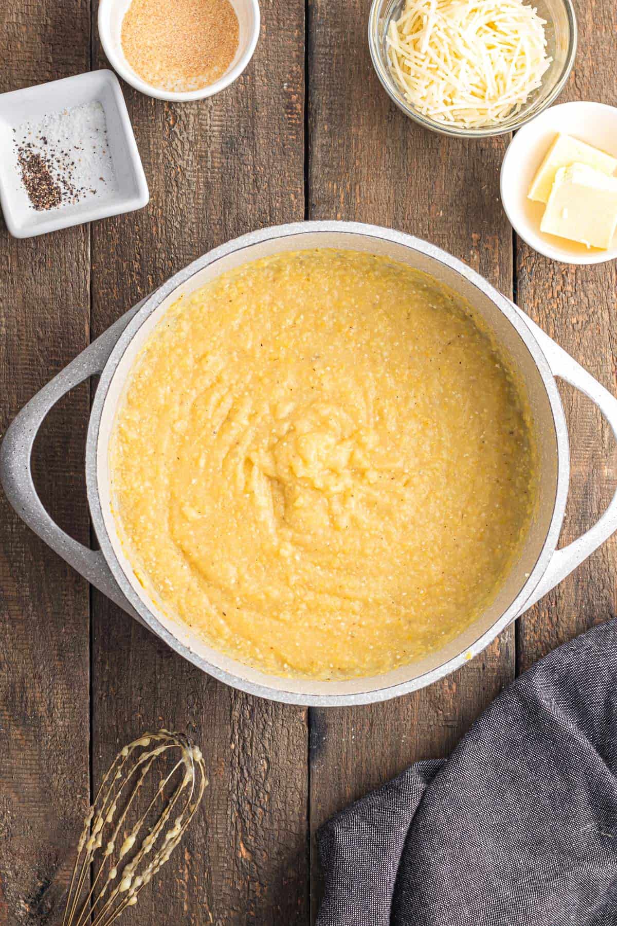 Cooked polenta in a big pot with other ingredients on the side.