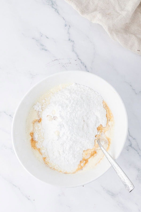 Some powdered sugar and cream in a mixing bowl.