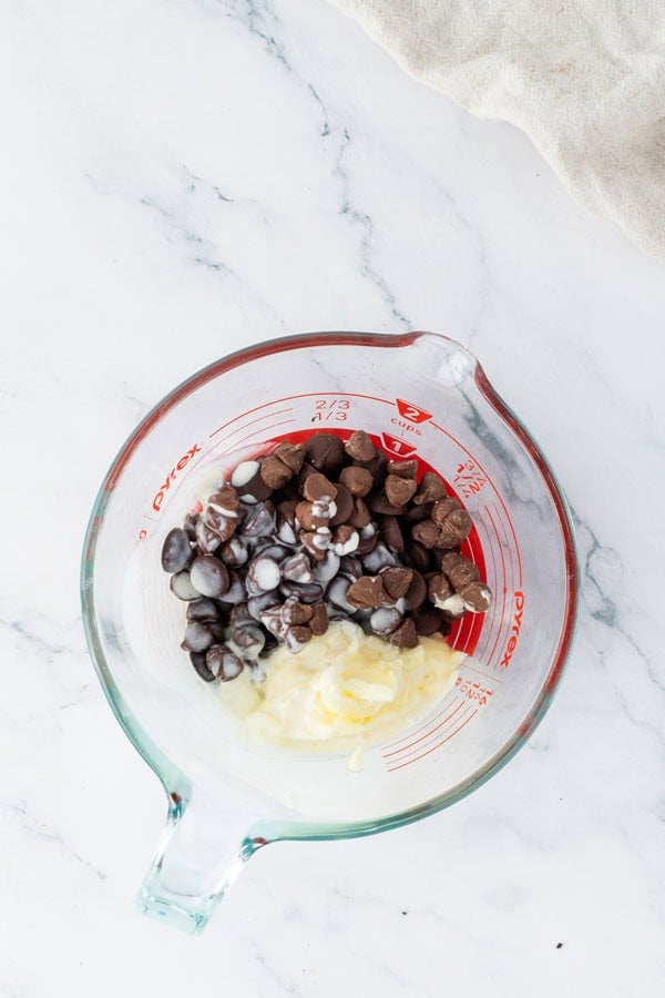 Some chocolate chips and butter in a glass measuring cup.