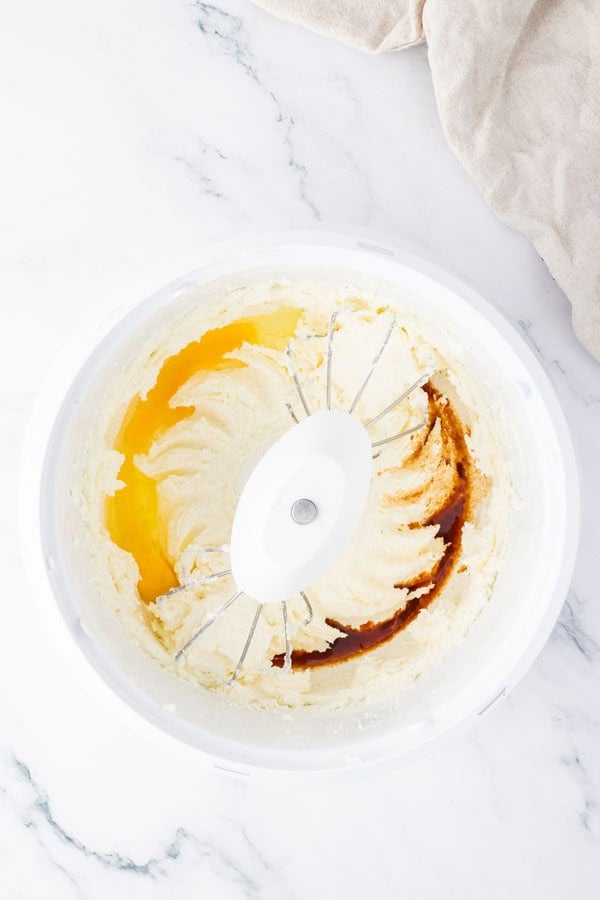 Mixing bowl with eggs, vanilla extract, and creamed butter and sugar.