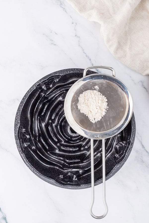A greased Bundt pan with a fine mesh strainer of flour.