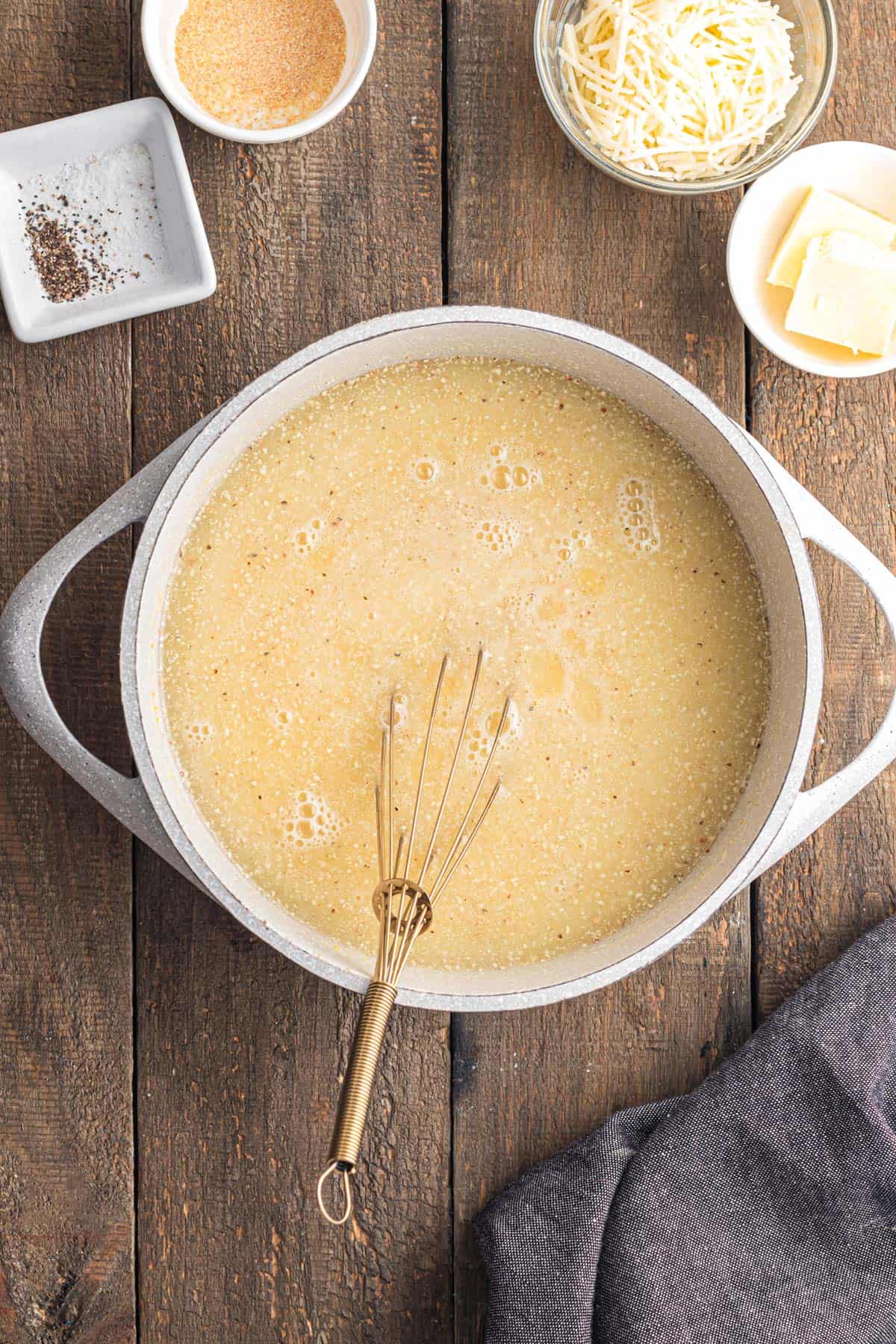 Polenta being whisked into a pot of boiling water.