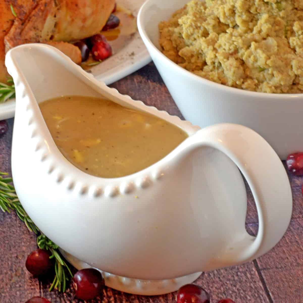 A big bowl of giblet gravy with some dressing in the background.